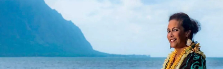 Faith Ako sitting in front of the ocean and and island.